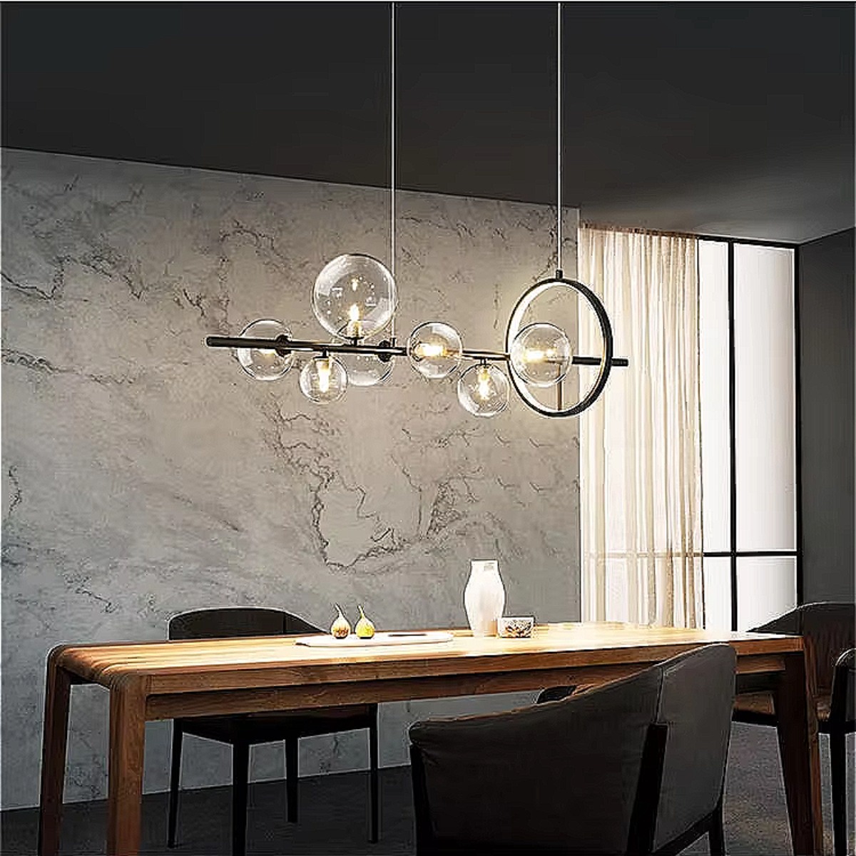 Modern-meets-vintage dining area illuminated by a sculptural black chandelier with glowing glass orbs, creating soft 3000K warmth above a styled table.
