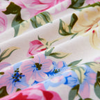 Close-up of floral fabric with pink, blue, and green flowers on a ivory duvet cover in romantic bedroom