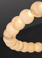 Natural alabaster bead ring arc close-up showing warm honey glow through stone – sculptural luxury chandelier detail | LINKORI AURELIA