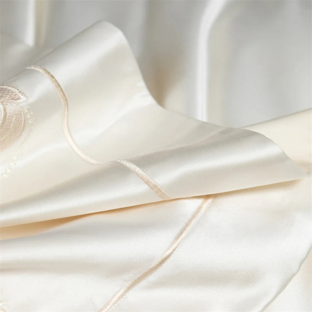 Romantic floral bedding set featuring hand-embroidered blush and powder blue flowers on cream satin cotton