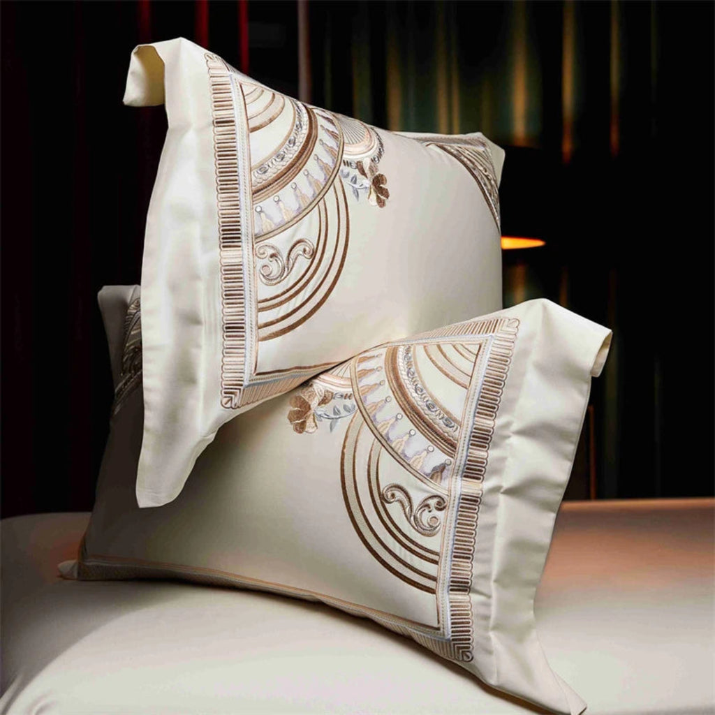 Ivory gold duvet cover set with Art Deco embroidered border on luxury hotel bed"