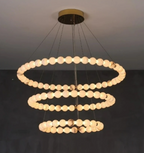 alabaster chandelier in daylight — Spanish alabaster orbs on 
brushed gold 3-tier ring frame, soft natural translucent glow, high ceiling fixture | LINKORI AURELIA