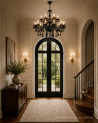 Black crystal entryway chandelier with candle-style bulbs in a traditional foyer with staircase and arched doors