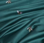 Detailed view of whimsical bee embroidery stitched onto rich green duvet cover – LINKORI H. Bee design highlight