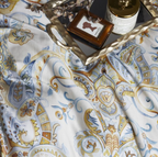  Detailed close-up of paisley and floral print in golden beige, blue, and ochre — inspired by grains, leaves, and vintage scrollwork.