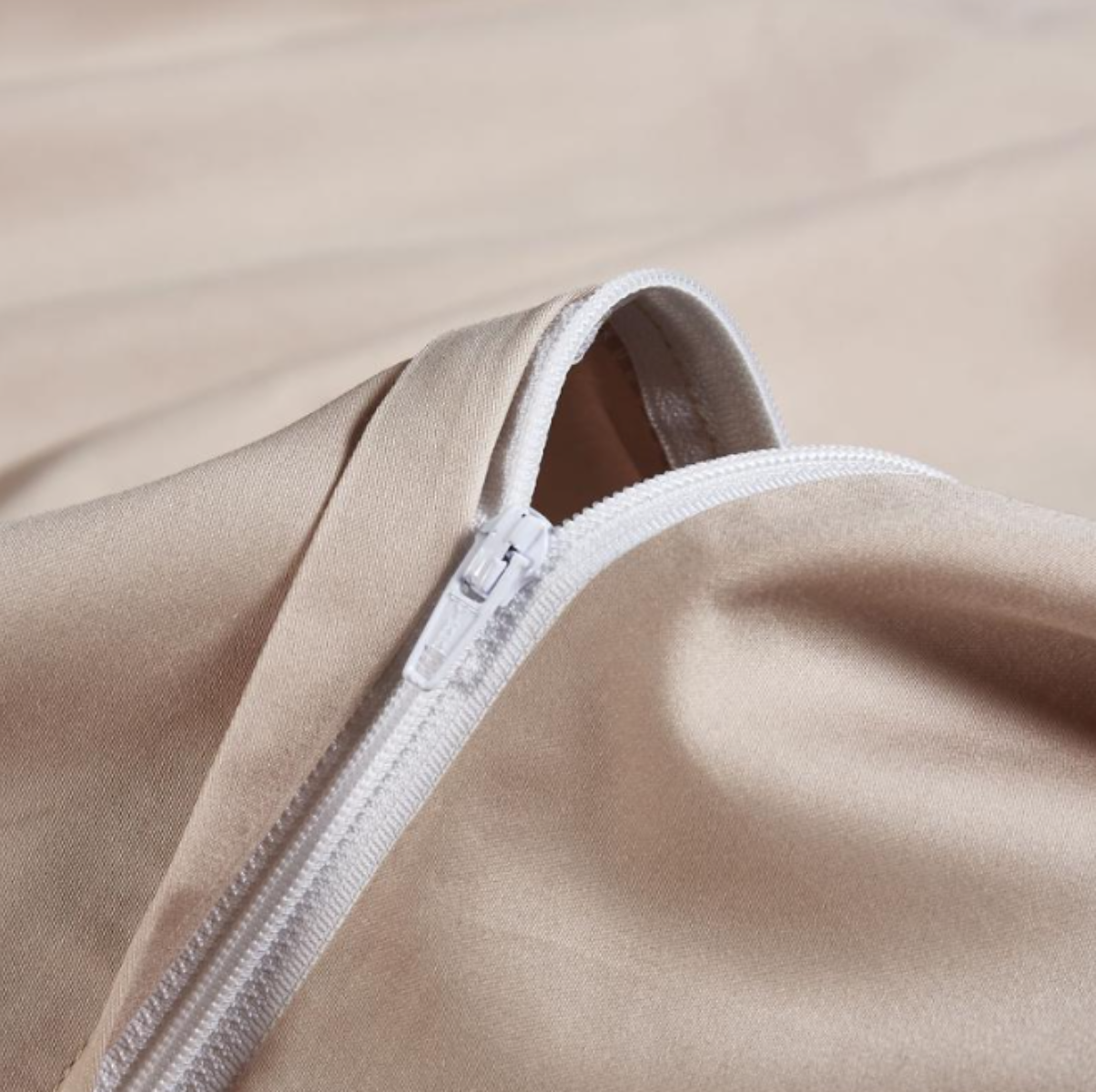 Close-up of hidden zipper detail on beige duvet cover — seamless closure with smooth stitching on silky cotton.