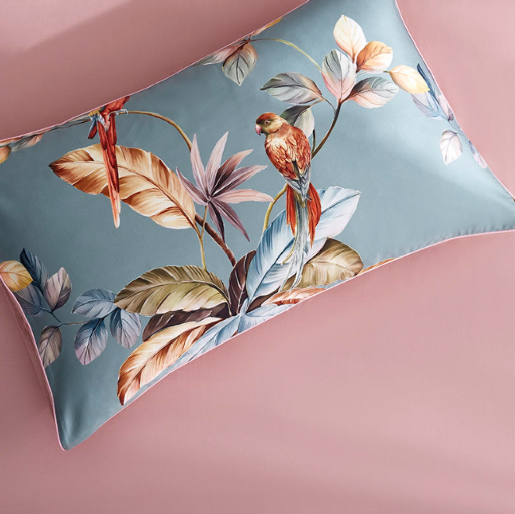 Close-up of tropical parrot print pillowcase on blush pink flat sheet, made of 100% Egyptian cotton – LINKORI Livelic