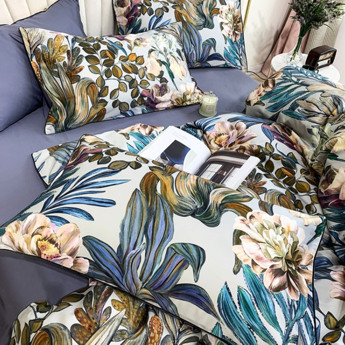 Two botanical pillows resting on a purple flat sheet, layered with the edge of the floral Egyptian cotton duvet cover.