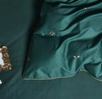 Close-up of matching deep green flat sheet and bee-embroidered duvet cover in 100% Egyptian cotton