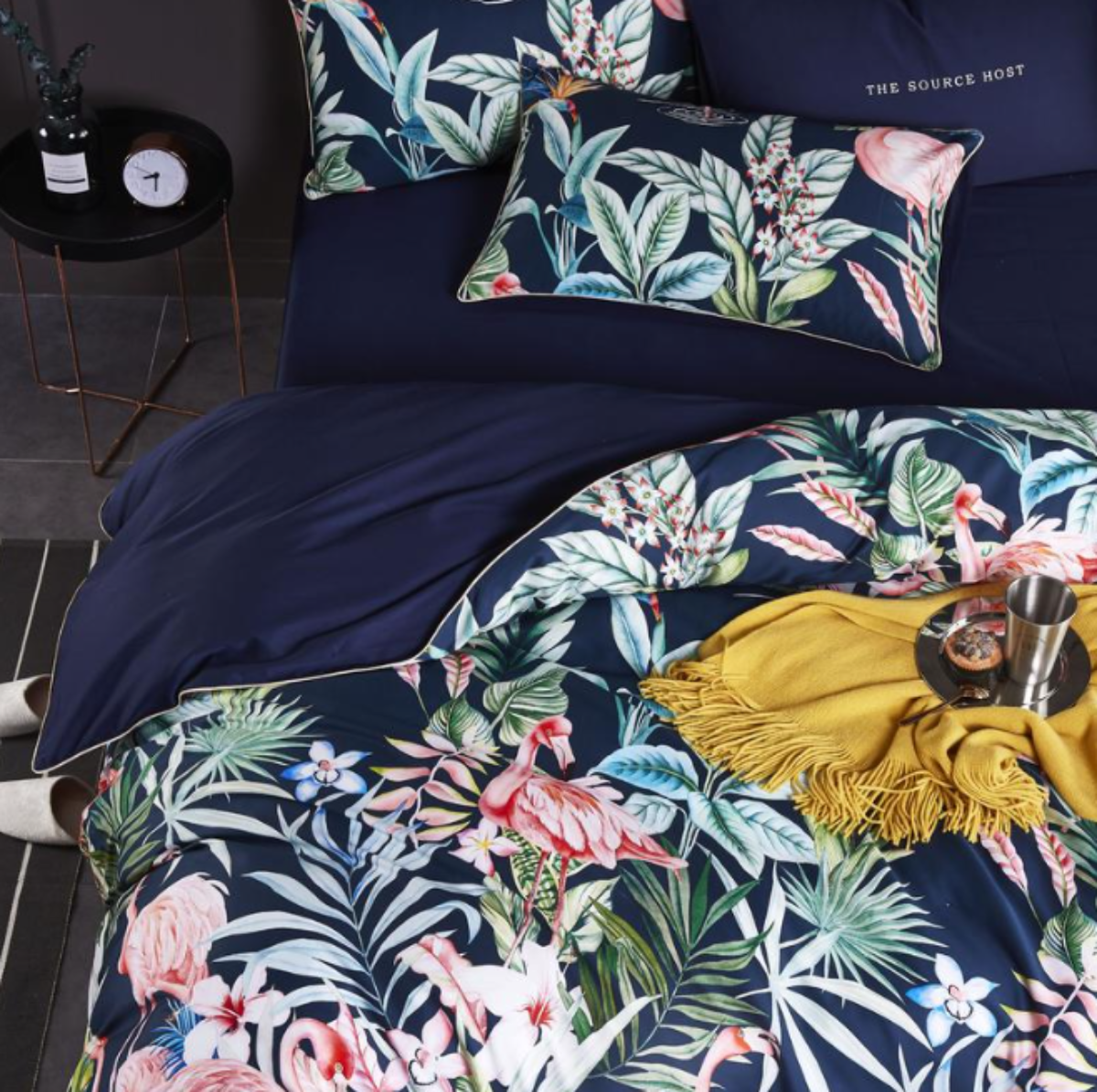 Angled close-up of duvet cover, flat sheet, and pillows featuring exotic jungle motifs — vibrant colors over deep navy bedding base.