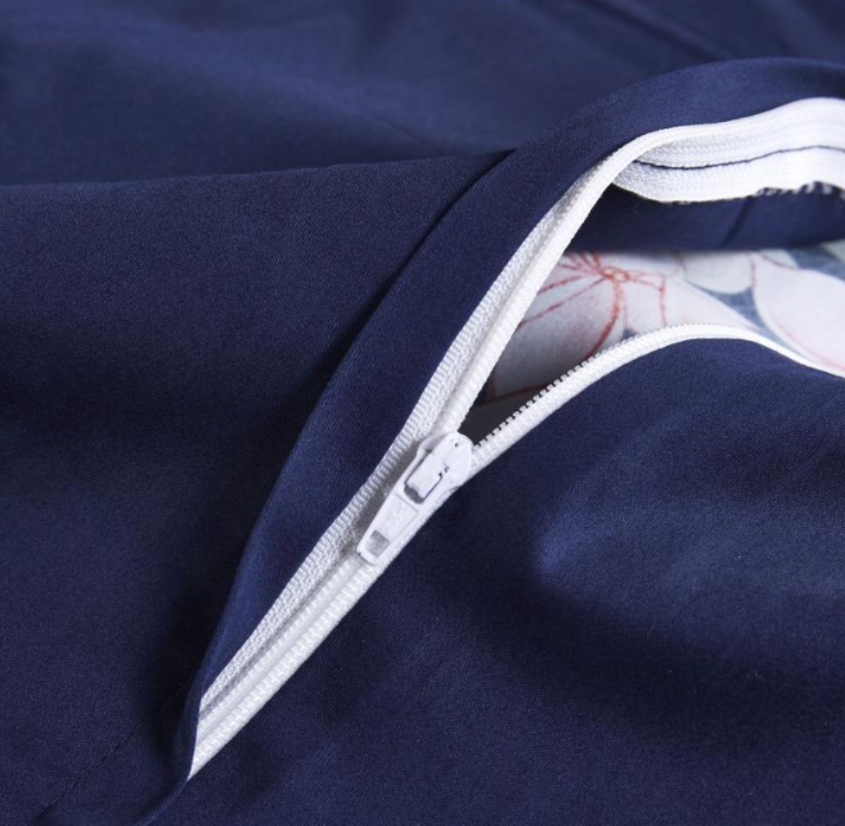 Close-up of concealed zipper on navy duvet cover — seamless closure blending into silky botanical fabric.