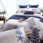 Angled view of Blue Coral ocean-themed duvet cover on a wood floor, styled with starfish and decorative pillows