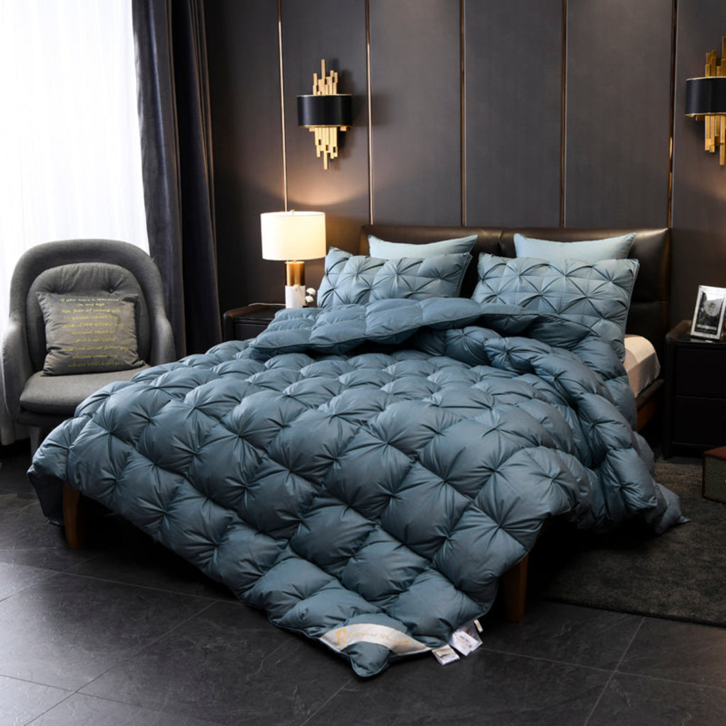 Side perspective of the comforter highlighting its puffed texture and deep blue color against a modern upholstered bed.