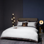Side view of minimalist white satin bedding with soft luster, paired with a dark flat sheet for contrast and depth.