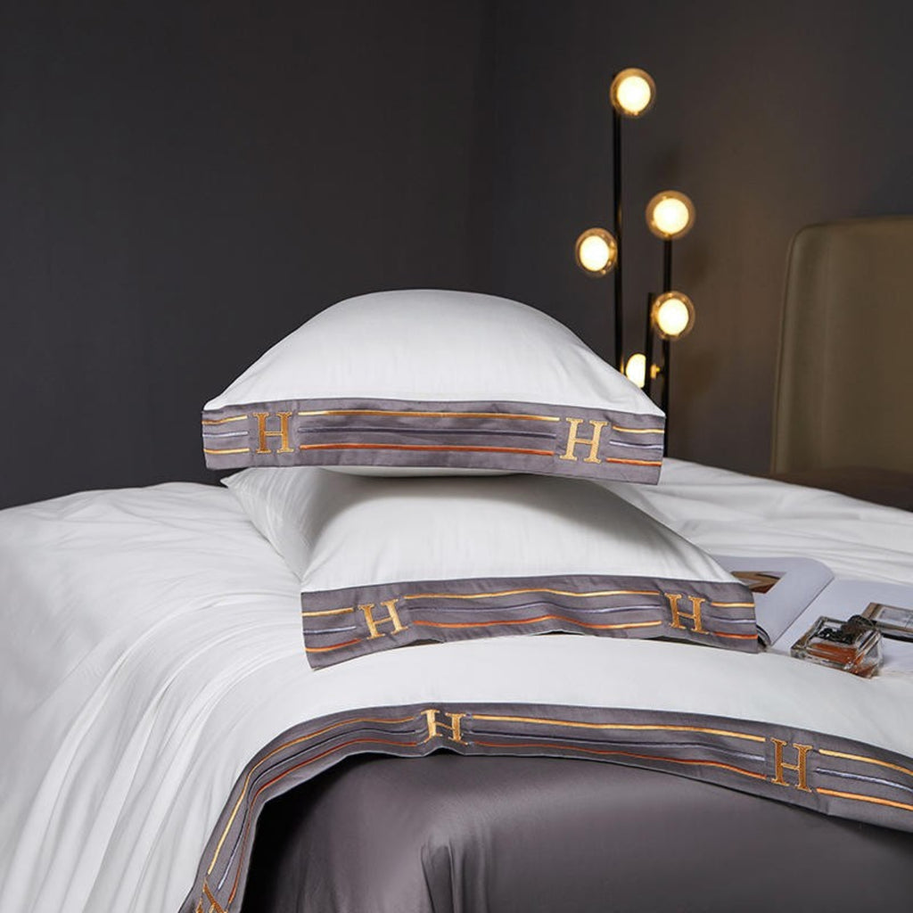 Two white pillows and silky duvet cover resting on dark grey flat sheet, showing crisp contrast and elegant layering.