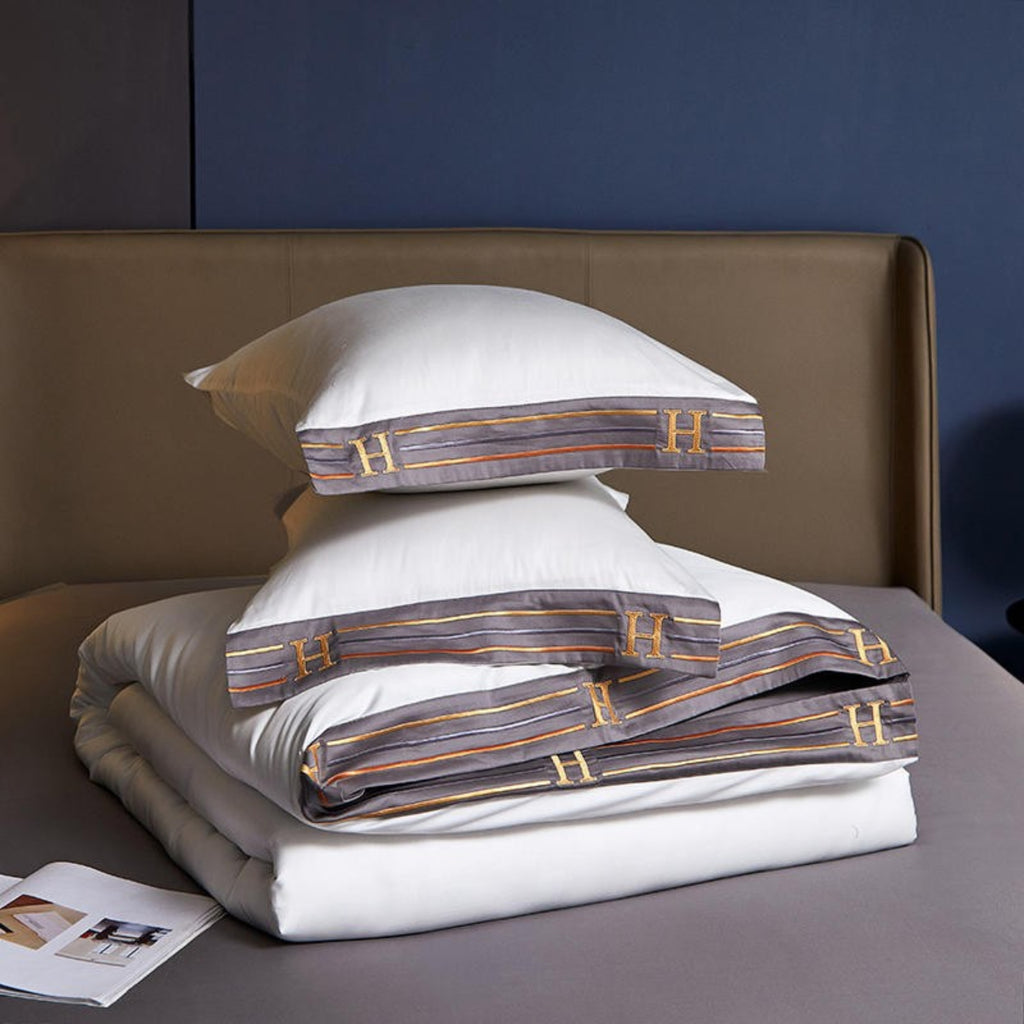 Folded duvet cover placed over flat sheet with two stacked pillows — emphasizing smooth texture and neat styling.