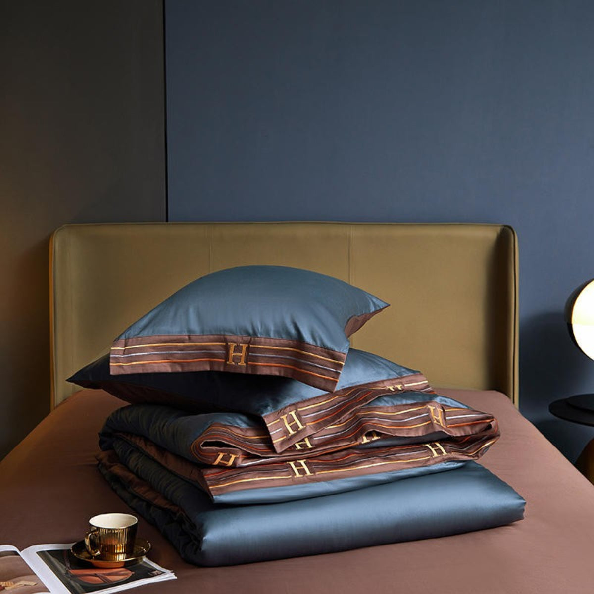Blue Egyptian cotton duvet and pillow folded neatly on brown satin flat sheet – luxury bedding styling in modern interiors