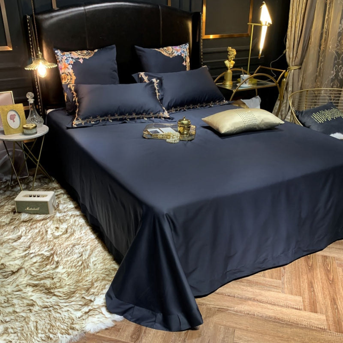 Close shot of flat black sheet paired with four matching pillowcases, emphasizing minimal elegance and bedding texture.
