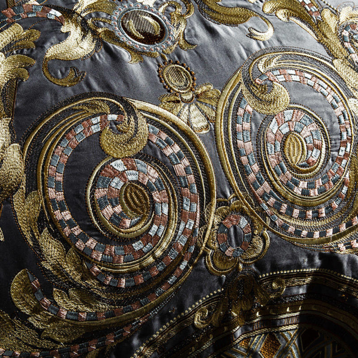 Close-up of gold embroidered motif on grey pillowcase, showcasing intricate baroque pattern and stitching quality.