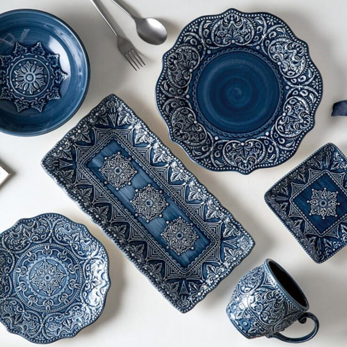 Top-down flat lay of Gratique blue patterned plates, bowls, and mugs – complete baroque-style dinner set