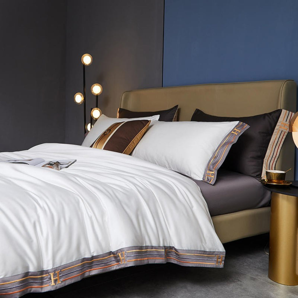 Angled side view of white satin duvet layered over grey flat sheet, capturing fabric flow and contemporary styling.