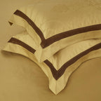 Two pillowcases resting on gold flat sheet – part of the Blangdra luxury bedding set by LINKORI