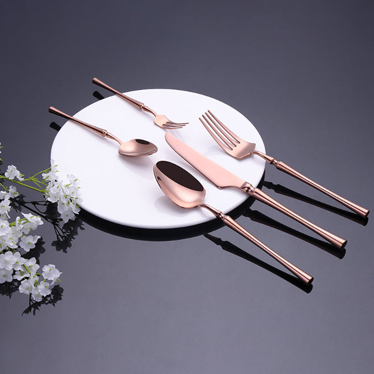 Flatware set laid out in separated arrangement – rose gold knife, forks, and spoons in full sculptural detail